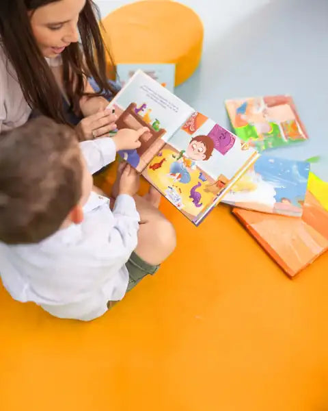 A child turning the pages of a storybook on the floor