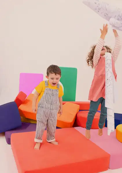 Two kids playing with a giant coloring roll